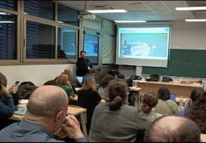 Lecturer presenting slides to an audience in a classroom during a seminar.